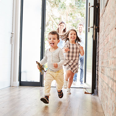 Children run into their new home as parents follow behind them